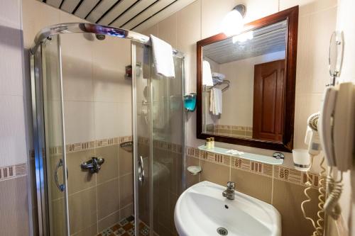 a bathroom with a shower and a sink and a mirror at Sea point Quality Resort in Antalya