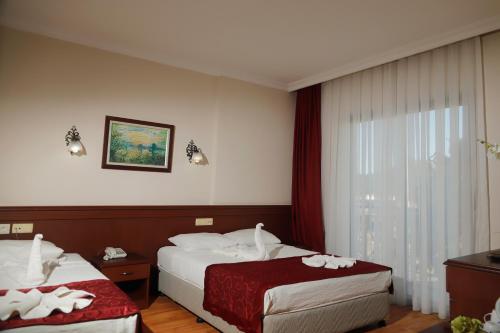 a hotel room with two beds and a window at Sea point Quality Resort in Antalya