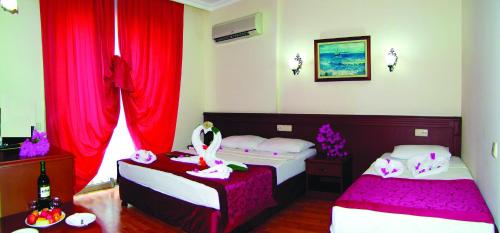 a bedroom with two beds and red curtains at Sea point Quality Resort in Antalya