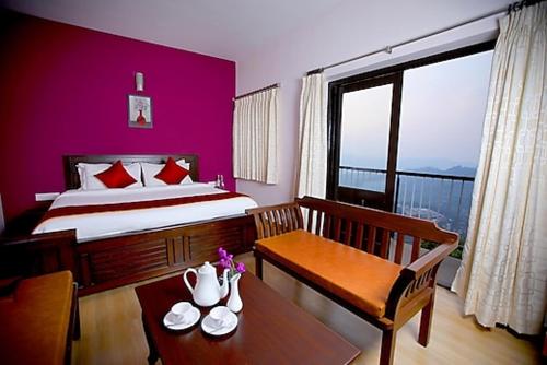 um quarto de hotel com uma cama e uma mesa com uma mesa sidx sidx em The Garudan Mountain View Residency em Kodaikanal