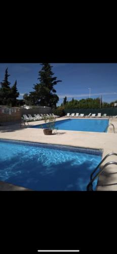 une grande piscine avec de l'eau bleue et des chaises dans l'établissement Mobilhome 6 personnes climatisé, à Villeneuve-lès-Maguelone