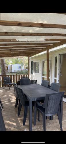 une table et des chaises noires sur une terrasse dans l'établissement Mobilhome 6 personnes climatisé, à Villeneuve-lès-Maguelone