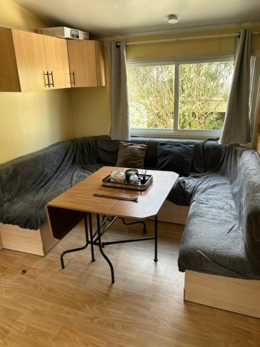sala de estar con sofá y mesa en Mobilhome 6 personnes climatisé, en Villeneuve-lès-Maguelonne