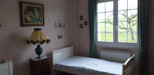 a bedroom with a bed with a lamp and a window at Maison de campagne avec piscine in Le Blanc