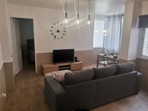 a living room with a couch and a clock on the wall at Enjoy Lisboa 2! - Near Metro in Amadora