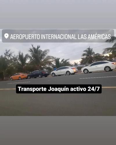 a sign for the international las americas with cars parked at transporte Joaquín me dedico al servicio de taxi desde el Aeropuerto las Américas a todas partes del país in Santo Domingo