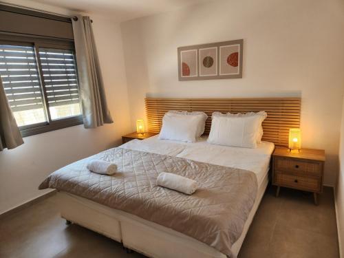a bedroom with a large bed with two lamps on it at בצל ההר in Ein Tamar 