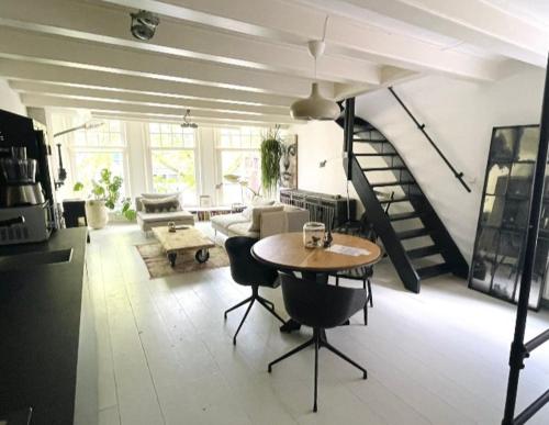 a living room with a table and a spiral staircase at Volledige bovenwoning binnenstad in Leeuwarden