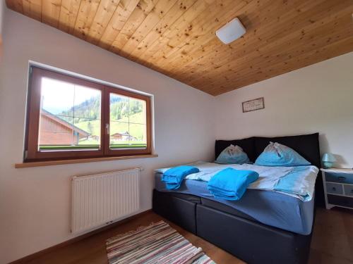 1 dormitorio con cama con sábanas azules y ventana en APPARTEMENT Brix, en Pichl