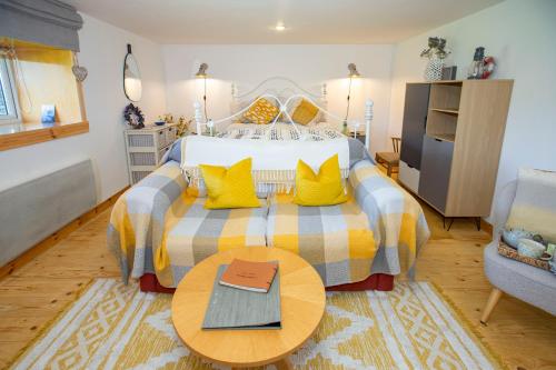 Un dormitorio con una cama con almohadas amarillas y una mesa. en Crofters Retreat 
