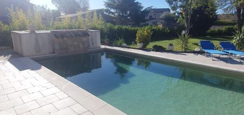 - une piscine avec deux chaises bleues dans la cour dans l'établissement Chez Dom & Albert, à Saint-Cézaire-sur-Siagne