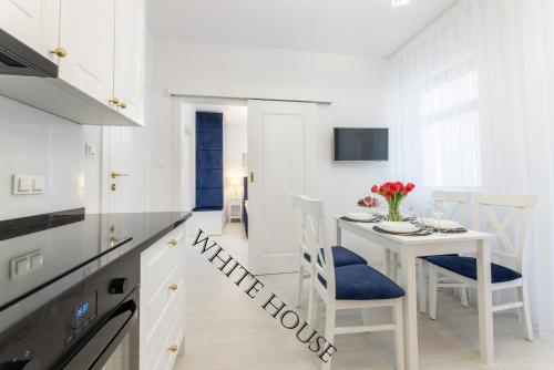 - une cuisine blanche avec une table et des chaises blanches dans l'établissement Apartament White House Ustka Granatowy 2B, à Ustka