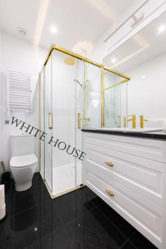 La salle de bains blanche est pourvue d'une douche et de toilettes. dans l'établissement Apartament White House Ustka Granatowy 2B, à Ustka