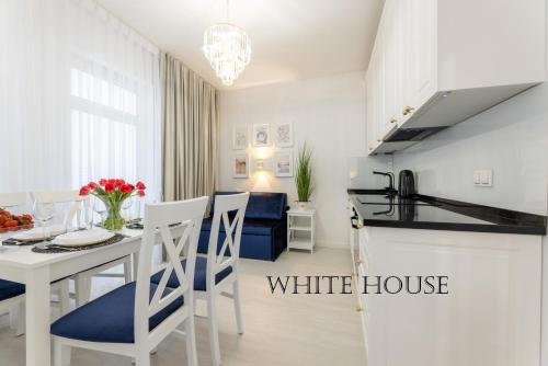 une cuisine blanche et une salle à manger avec une maison blanche dans l'établissement Apartament White House Ustka Granatowy 2B, à Ustka