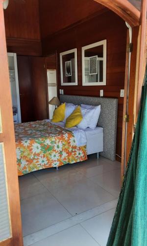 um quarto com uma cama com almofadas amarelas em Refúgio Hangarana em Angra dos Reis