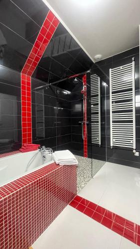 une salle de bain noire et rouge avec une baignoire et une douche dans l'établissement Comme à la maison, à Couffy