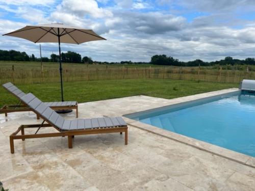 einen Stuhl und einen Regenschirm neben einem Pool in der Unterkunft Charmante petite maison avec piscine in Monguillem