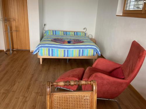 a bedroom with a bed and a red chair at Chalet Bergoase in Hohfluh