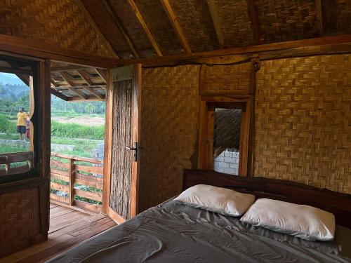 a bedroom with a bed in a room with a window at Padi Bungalows in Tetebatu