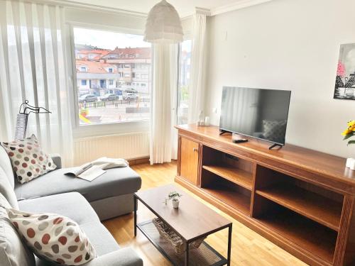 a living room with a couch and a television at Apartamento San Juan. Piscina y Parking privado. in San Juan de la Arena