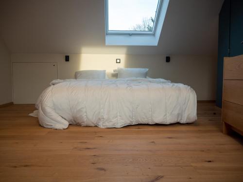 a bedroom with a bed with a white comforter at Juste à Côté - duplex tout confort in Esneux