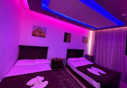 two beds in a room with purple lights at Pyramids station View in Cairo