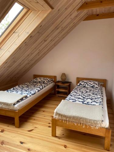 two beds in a attic room with wooden ceilings at Agroturystyka Łazory nad Tanwią in Łazory