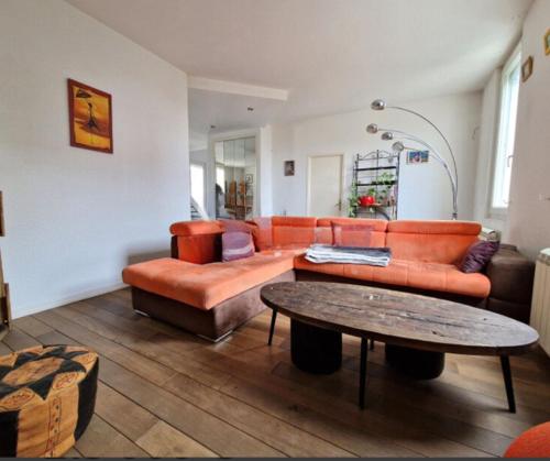 a living room with an orange couch and a table at Appartement spacieux et confortable in Valence