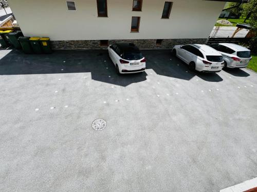 dos autos estacionados en un estacionamiento al lado de un edificio en Apartma Lip, en Rateče
