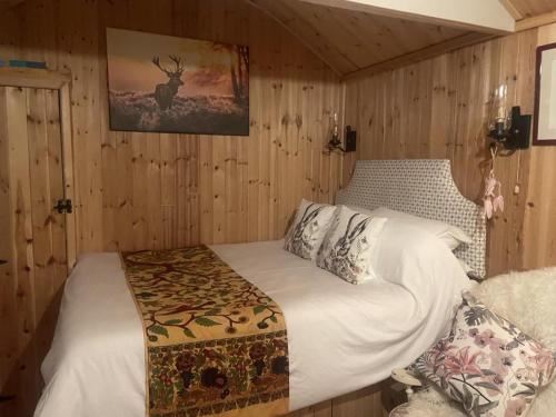 Lovely shepherds hut in Cornwall في كاميلفورد: غرفة نوم بسرير في غرفة بجدران خشبية