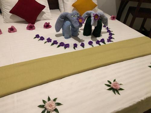 two figurines of elephants on a bed with purple flowers at Eagle Eye Yala in Yala