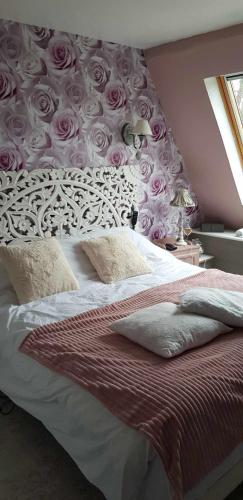 - une chambre avec un lit orné de roses roses sur le mur dans l'établissement maison cosy et spa zen au chemin du bonheur, à Hondschoote