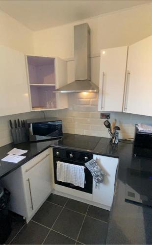 a kitchen with white cabinets and a black counter top at Edinburgh City Centre & Airport 2 Bedroom Apartment in Edinburgh