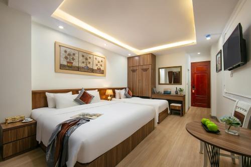 a hotel room with a large bed and a table at Tunger Premium Hotel & Travel in Hanoi