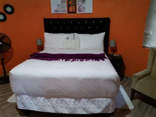 ein Schlafzimmer mit einem großen weißen Bett und einem Stuhl in der Unterkunft Lungakaunakho Country Lodge in Port Edward