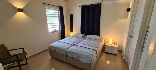 - une chambre avec un lit, une fenêtre et une chaise dans l'établissement Bonaire Village Villa 23, à Kralendijk