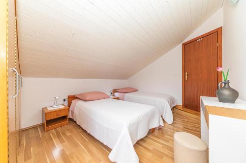 2 Betten in einem Zimmer mit weißen Wänden und Holzböden in der Unterkunft Apartments Iskra in Split
