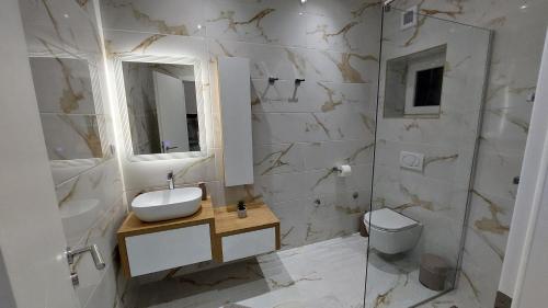 a white bathroom with a sink and a toilet at Premier House by RD Group in Korenica