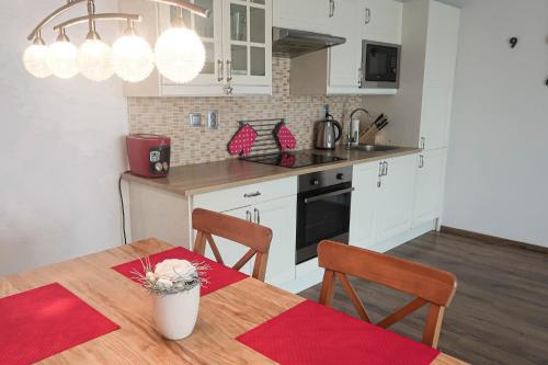 a kitchen with a wooden table and a kitchen with white cabinets at Sweet Home in Příchovice