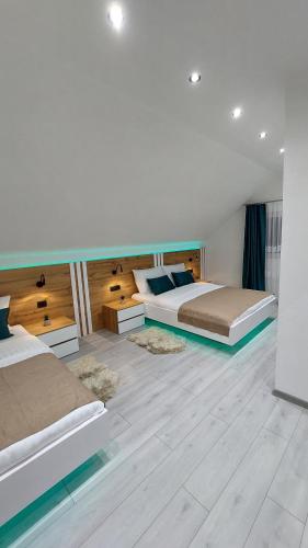 two beds in a large room with wooden floors at Premier House by RD Group in Korenica