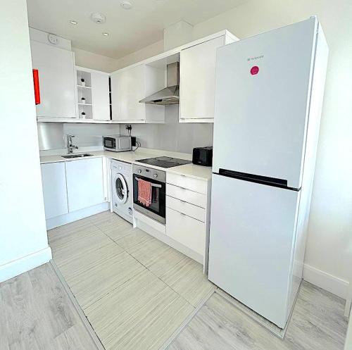 een witte keuken met een koelkast en een fornuis bij Harrow Apartments in Londen