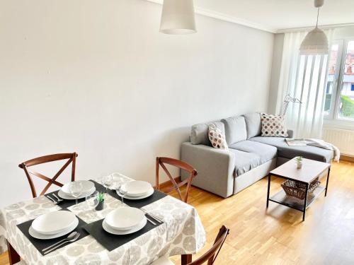 a living room with a table and a couch at Apartamento San Juan. Piscina y Parking privado. in San Juan de la Arena