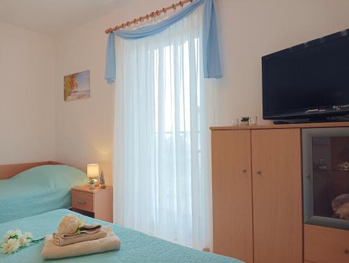 Apartment Milotić في لوفران: غرفة نوم بسرير وتلفزيون ونافذة