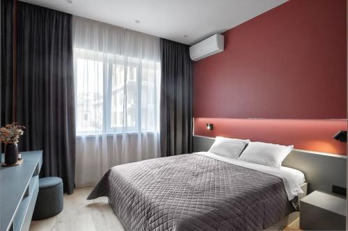 a bedroom with a bed and a red wall at Sea Moreto Apartment 2 in Burgas City
