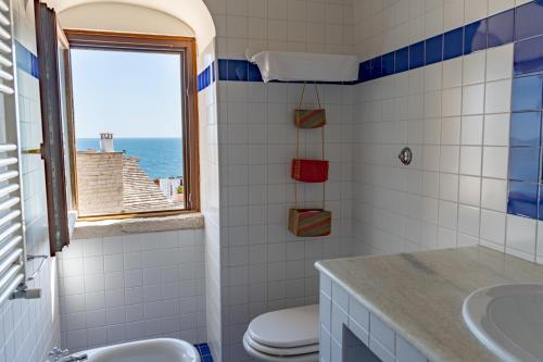 een badkamer met een wastafel, een toilet en een raam bij S. Martin Hotel in Giovinazzo