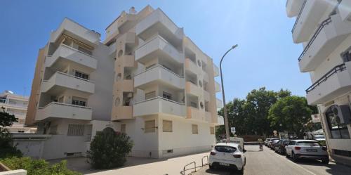 a tall white building with cars parked in front of it at Oceanic Opulence Delux Apartment in Monte Gordo
