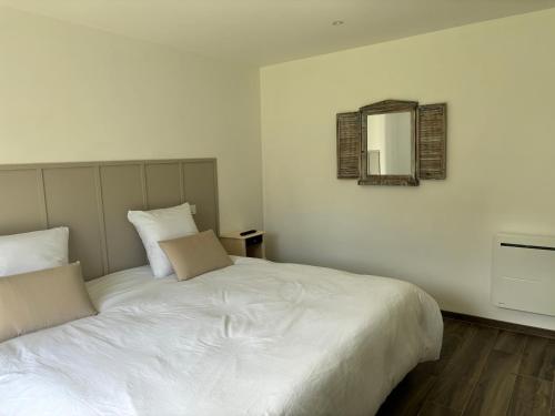 a bedroom with a large white bed and a mirror at La villa in Nernier