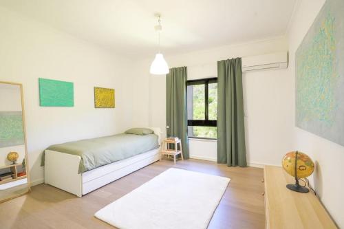 Schlafzimmer mit einem Bett und einem Fenster in der Unterkunft Stunning Duplex in Amadora in Amadora
