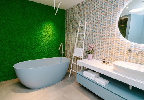 Etna Cottage Charming Bed and breakfast في نيكولوسي: حمام مع حوض استحمام وجدار أخضر
