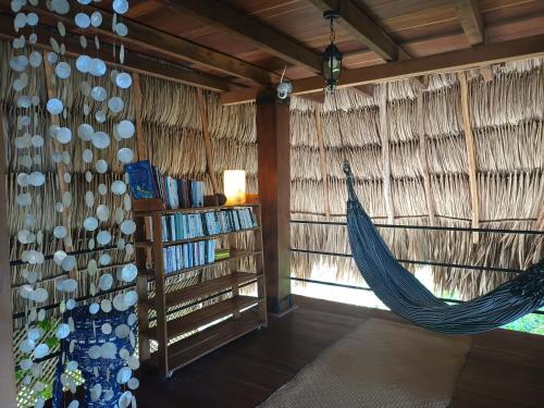 a hammock in a room with a book shelf at Alice Guesthouse in El Remate